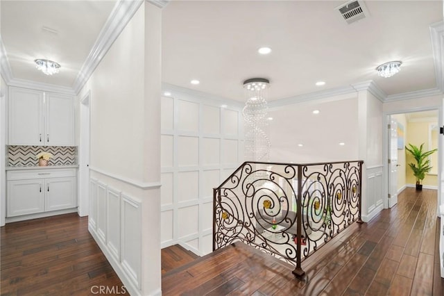 hall with a notable chandelier, crown molding, and dark wood-type flooring