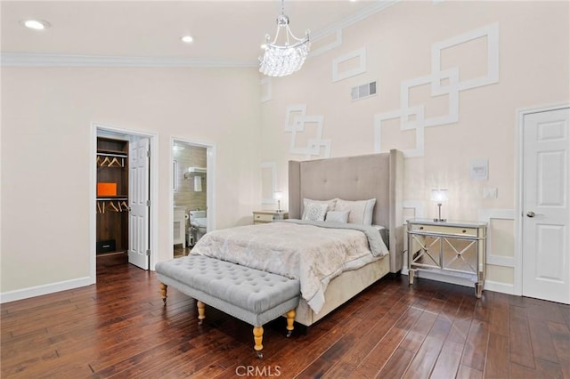 bedroom with connected bathroom, a spacious closet, dark hardwood / wood-style flooring, and ornamental molding