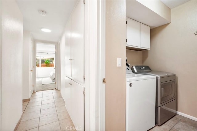 laundry area with separate washer and dryer, cabinets, and light tile patterned flooring