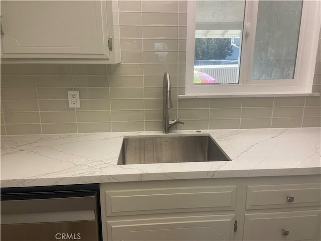 kitchen featuring light stone countertops, sink, white cabinetry, and decorative backsplash