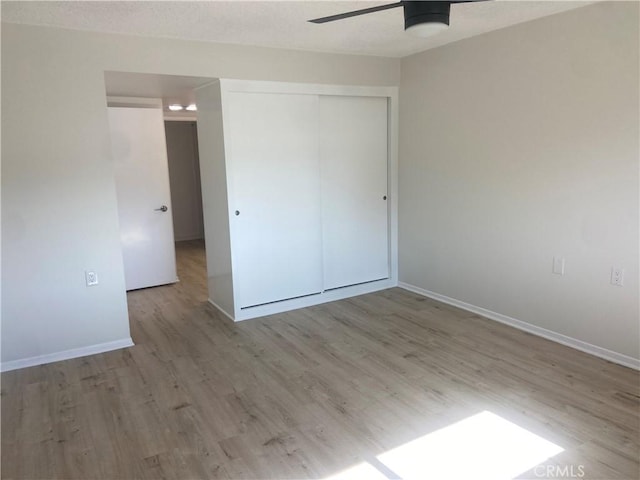 unfurnished bedroom with light wood-type flooring, a closet, and ceiling fan