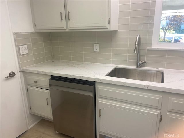 kitchen with sink, white cabinets, tasteful backsplash, and light stone countertops