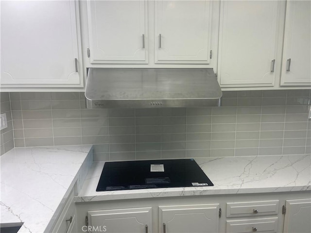 kitchen featuring white cabinets, backsplash, exhaust hood, and stovetop