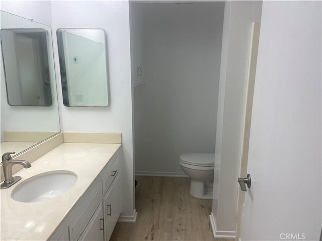 bathroom with hardwood / wood-style flooring, toilet, and vanity