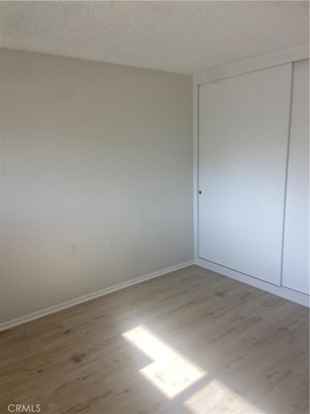 unfurnished bedroom with hardwood / wood-style floors, a closet, and a textured ceiling