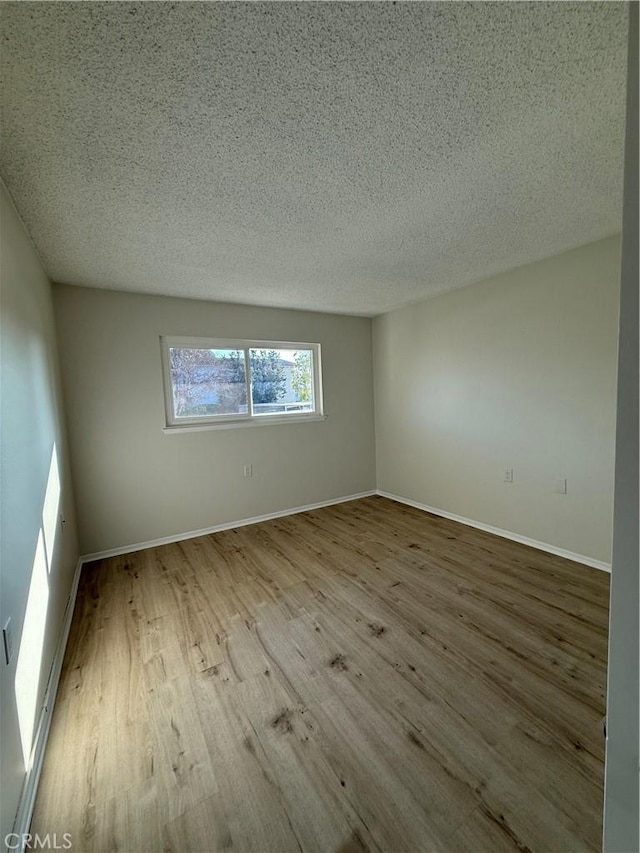 empty room with light hardwood / wood-style flooring and a textured ceiling