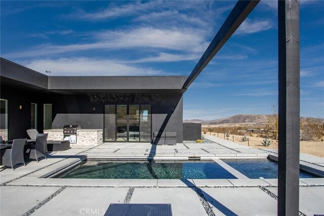 view of swimming pool with exterior kitchen, a patio area, area for grilling, and a mountain view