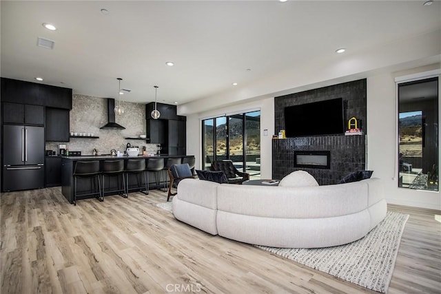 living room featuring a tile fireplace and light hardwood / wood-style flooring