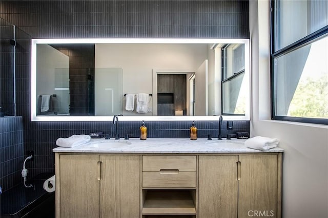 bathroom featuring vanity, decorative backsplash, and a tile shower