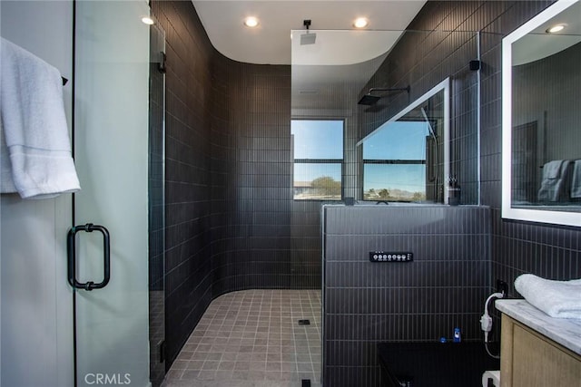 bathroom with vanity, an enclosed shower, and tile walls