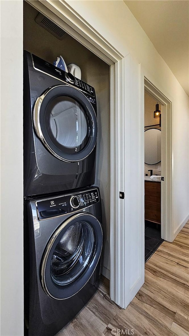 laundry room featuring stacked washer / drying machine and hardwood / wood-style floors