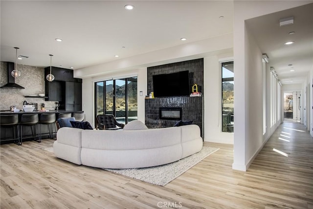 living room with a tile fireplace and light hardwood / wood-style floors