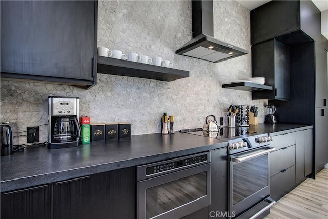 kitchen featuring wall oven, tasteful backsplash, stainless steel electric stove, built in microwave, and wall chimney exhaust hood