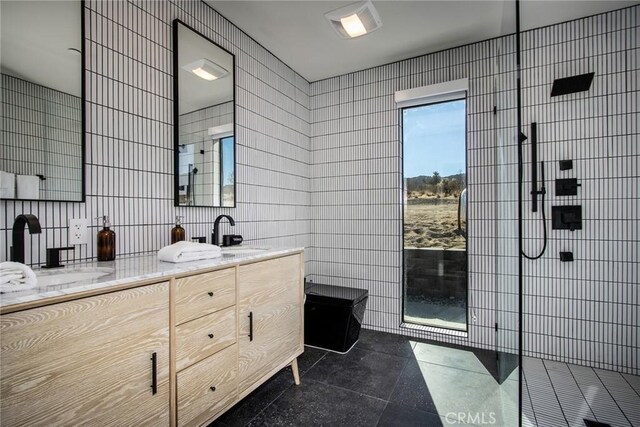 bathroom with tile walls, walk in shower, vanity, and tile patterned flooring