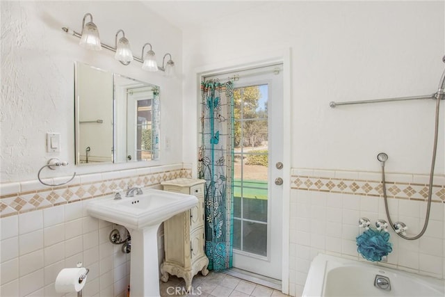 bathroom featuring tile patterned flooring, sink, tile walls, and bathing tub / shower combination