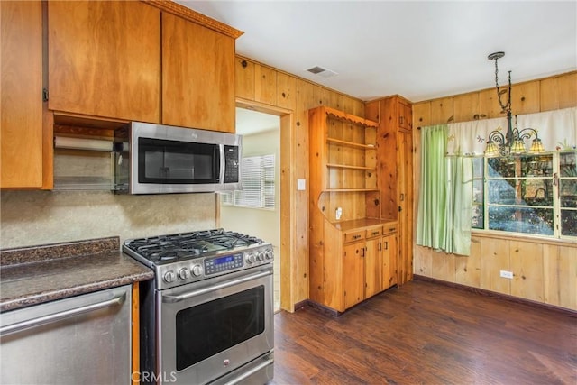 kitchen with appliances with stainless steel finishes, an inviting chandelier, plenty of natural light, and dark wood-type flooring