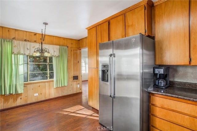 kitchen with an inviting chandelier, stainless steel refrigerator with ice dispenser, hanging light fixtures, dark hardwood / wood-style floors, and dark stone countertops