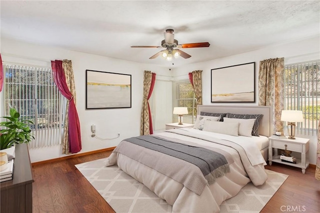 bedroom with multiple windows, dark hardwood / wood-style flooring, and ceiling fan