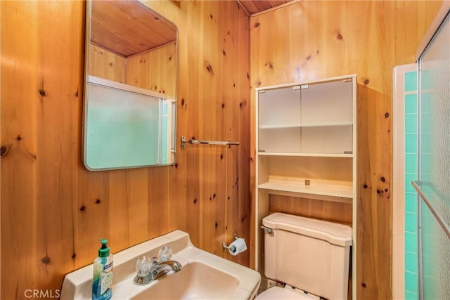 bathroom featuring toilet, sink, and wooden walls