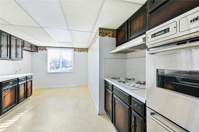 kitchen with a paneled ceiling, white gas cooktop, and dark brown cabinetry