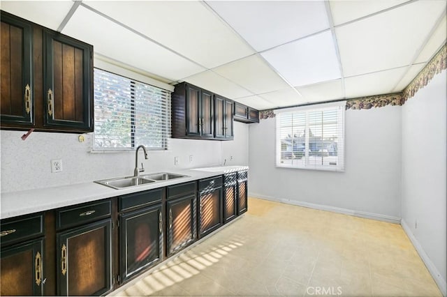 kitchen with dark brown cabinets, a drop ceiling, sink, and a wealth of natural light