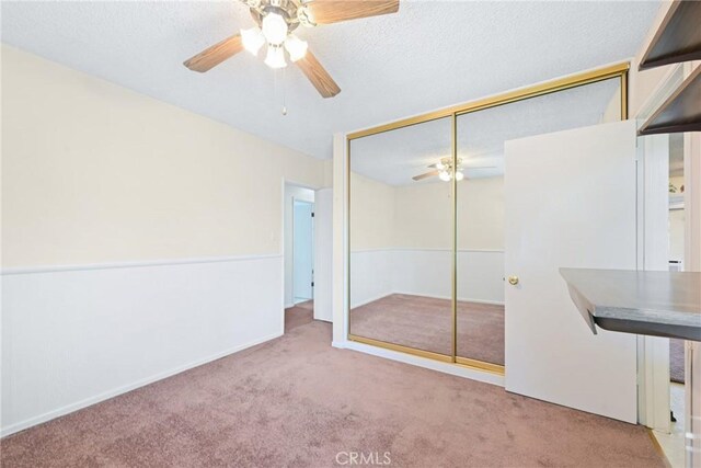 unfurnished bedroom with ceiling fan, light colored carpet, and a closet