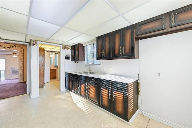 kitchen with dark brown cabinets, ceiling fan, a drop ceiling, and sink