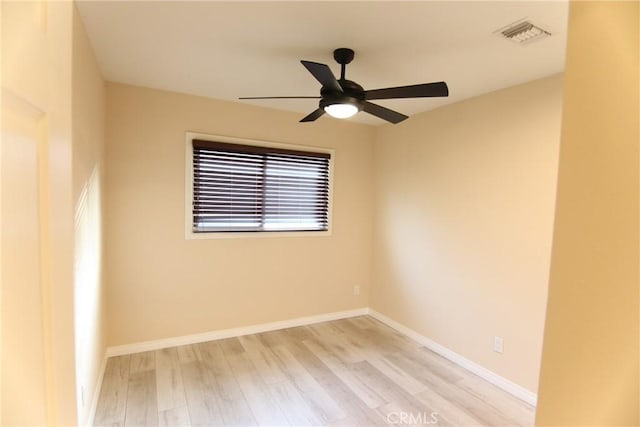 spare room with light wood finished floors, a ceiling fan, visible vents, and baseboards