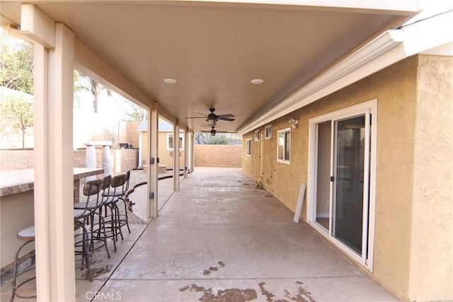 view of patio featuring exterior bar, fence, and a ceiling fan