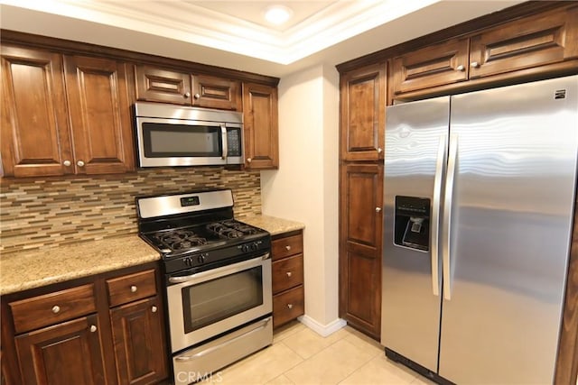 kitchen featuring light tile patterned floors, decorative backsplash, light stone countertops, stainless steel appliances, and crown molding