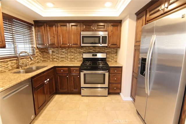 kitchen with stainless steel appliances, a raised ceiling, a sink, and decorative backsplash