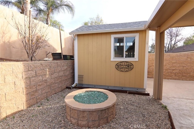 view of patio / terrace with an outbuilding, a fenced backyard, an outdoor fire pit, and a storage shed