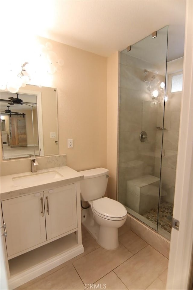 bathroom featuring toilet, tile patterned flooring, a tile shower, and vanity