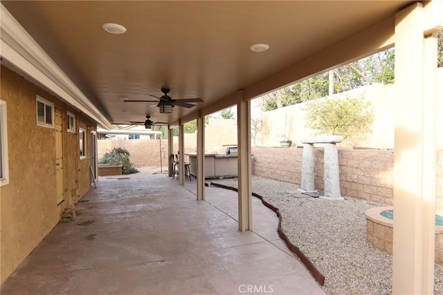 view of patio / terrace featuring an outdoor bar, a fenced backyard, and a ceiling fan