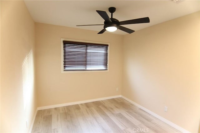 spare room with a ceiling fan, light wood-style flooring, and baseboards