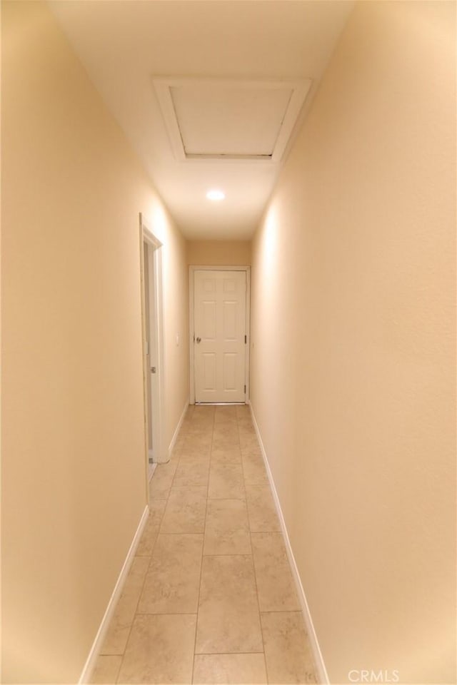 corridor with attic access, baseboards, and light tile patterned floors