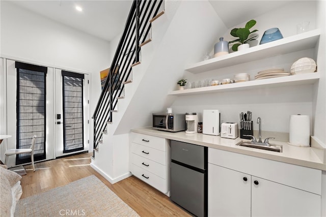 bar with white cabinetry, sink, and light hardwood / wood-style floors