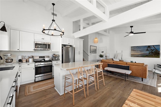 kitchen with white cabinetry, a breakfast bar, beamed ceiling, and appliances with stainless steel finishes