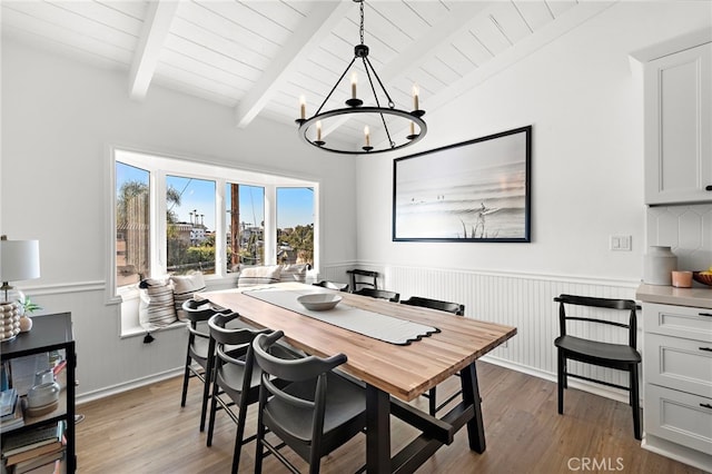 dining area featuring lofted ceiling with beams, light hardwood / wood-style floors, wooden ceiling, and a chandelier