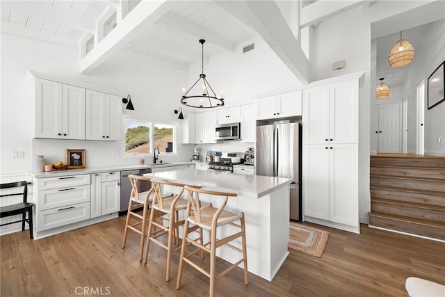 kitchen with beam ceiling, white cabinetry, and appliances with stainless steel finishes