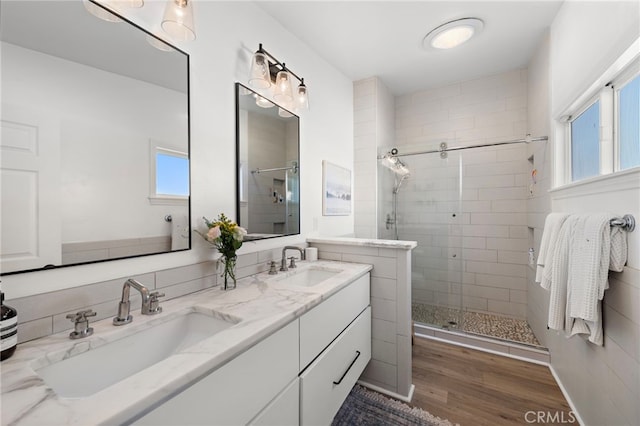 bathroom with a wealth of natural light, vanity, a shower with shower door, and hardwood / wood-style flooring