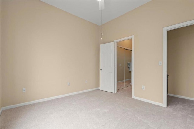 unfurnished bedroom featuring light carpet, a closet, and ceiling fan