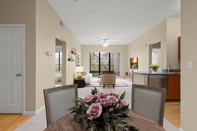 dining space with ceiling fan and light wood-type flooring