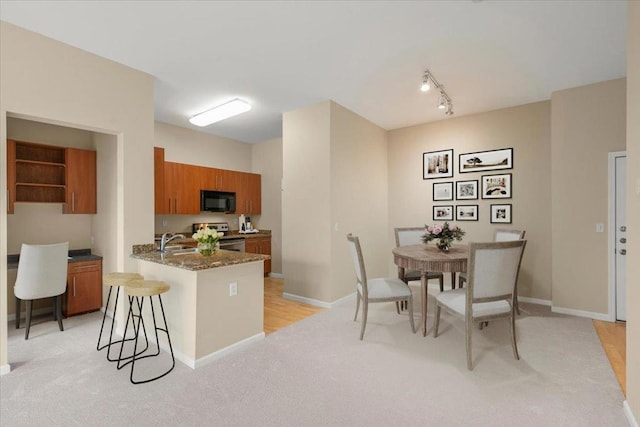 kitchen with light colored carpet, a kitchen breakfast bar, sink, and stainless steel range with electric stovetop