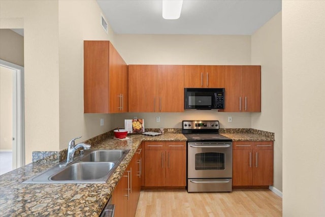 kitchen featuring stone counters, stainless steel electric range oven, sink, and light wood-type flooring