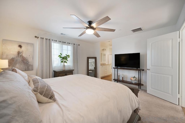 carpeted bedroom with ensuite bathroom and ceiling fan