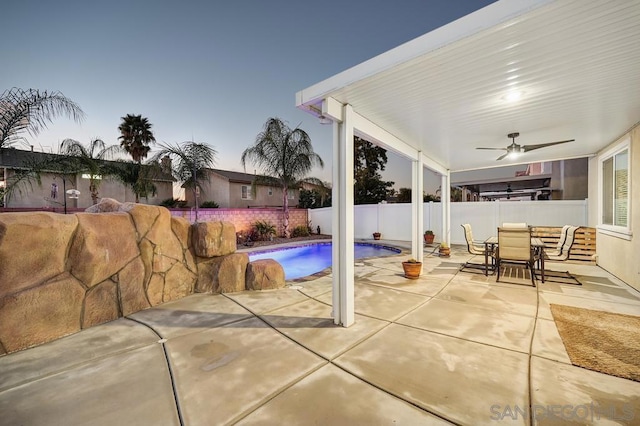 pool at dusk featuring a patio and ceiling fan