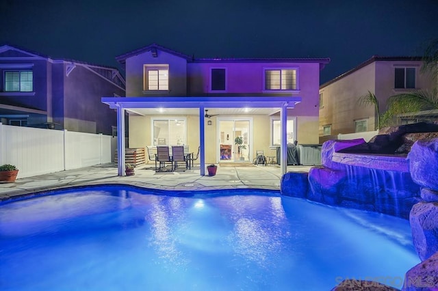 pool at night featuring a patio