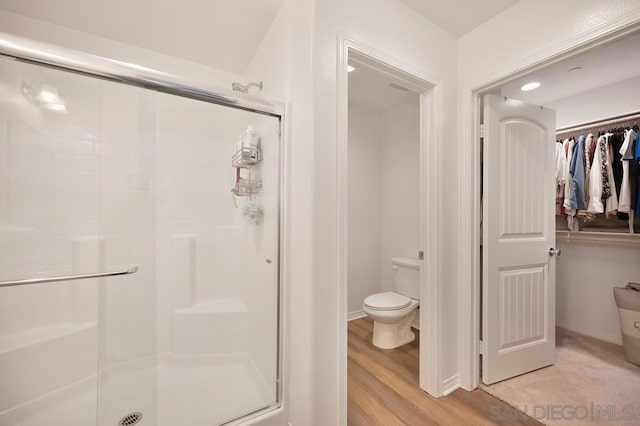 bathroom featuring toilet, an enclosed shower, and wood-type flooring