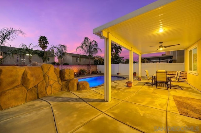 pool at dusk featuring a patio area and ceiling fan